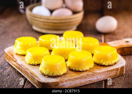 Caramella di tuorlo d'uovo, chiamata Quindim in Brasile, e Portogallo in brisa-do-Lis. Dolce dessert su rustico sfondo di legno Foto Stock