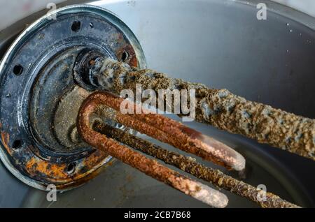 Flangia del riscaldatore dell'acqua con anodo, sensore di temperatura ed elemento riscaldante elettrico. Primo piano di un vecchio dettaglio di scaldabagno. Assistenza e riparazione. Selettivo Foto Stock