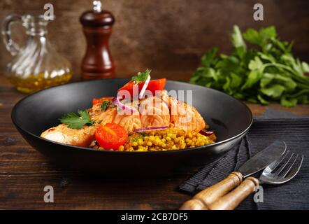 Un piatto con delizioso filetto di salmone, pomodori ciliegini arrostiti e grano saraceno Foto Stock