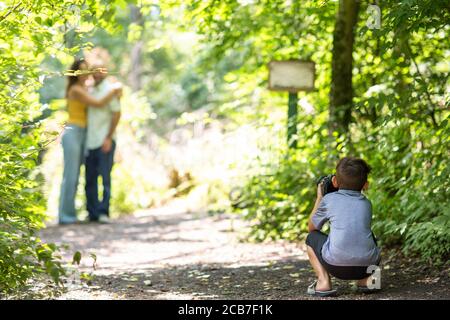 Ragazzino che fotografa i suoi genitori nei boschi. Foto Stock