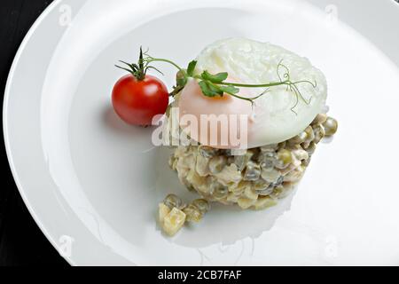 Insalata russa Olivier servita con uovo in camicia sulla parte superiore Foto Stock