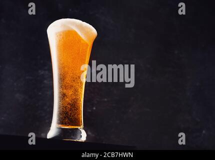 Un lungo bicchiere di birra su sfondo nero con copia spazio