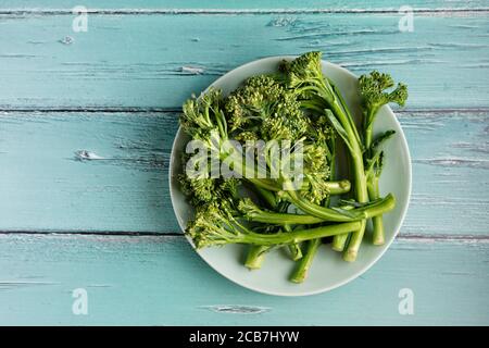 Vista dall'alto di un piatto verde con broccolini su rustico sfondo blu chiaro Foto Stock