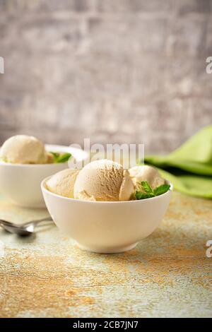 Gelato alla vaniglia in ciotole bianche su sfondo pastello Foto Stock