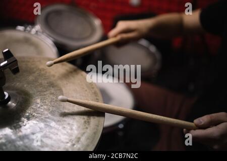 Mani maschili con drumsticks che suonano set di tamburi. Batterista maschio corto che tiene i drumsticks di legno e gioca la batteria kit. Foto Stock