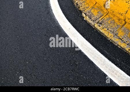 Dettaglio segnaletica stradale, banda riflettente bianca curva a una rotatoria. Foto Stock