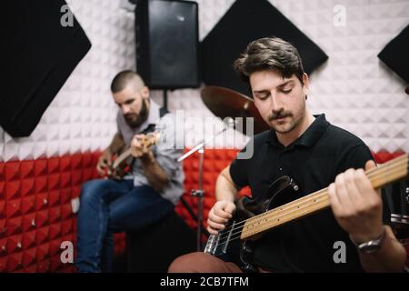 Giovani chitarristi maschili che suonano in studio di registrazione musicale Foto Stock