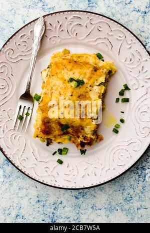 Un pezzo di lasagna appena sfornata con una crosta tostata su una piastra Foto Stock