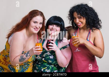 Più taglia donne che fanno festa. Ragazze multietniche curvy che indossano abiti e si divertono Foto Stock