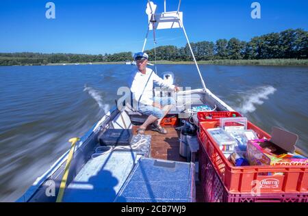 Diemitz, Germania. 06 agosto 2020. Jens Winkelmann è in movimento con il suo chiosco d'acqua sul Vilzsee di fronte alla serratura di Diemitz e fornisce ai vacanzieri su case galleggianti, yacht e canoe ghiaccio, bevande fredde o pesce appena affumicato. (Girato con un lungo periodo di esposizione) ogni giorno in stagione si trova sui corsi d'acqua e sul lago al confine con lo stato del Brandeburgo e del Meclemburgo per un massimo di 80 chilometri. Il Brandeburgo ha convertito la sua vecchia chiatta lunga quattro metri in una sorta di "consumo galleggiante" con un congelatore e scatole di conservazione del fresco. Credit: Jens Büttner/dpa-Zentr/dpa/Alamy Live News Foto Stock