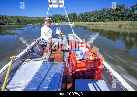 Diemitz, Germania. 06 agosto 2020. Jens Winkelmann è in movimento con il suo chiosco d'acqua sul Vilzsee di fronte alla serratura di Diemitz e fornisce ai vacanzieri su case galleggianti, yacht e canoe ghiaccio, bevande fredde o pesce appena affumicato. (Girato con un lungo periodo di esposizione) ogni giorno in stagione si trova sui corsi d'acqua e sul lago al confine con lo stato del Brandeburgo e del Meclemburgo per un massimo di 80 chilometri. Il Brandeburgo ha convertito la sua vecchia chiatta lunga quattro metri in una sorta di "consumo galleggiante" con un congelatore e scatole di conservazione del fresco. Credit: Jens Büttner/dpa-Zentr/dpa/Alamy Live News Foto Stock