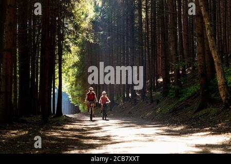 Madre e figlio in bicicletta nel percorso forestale al lago Millstatter, Millstatt, Carinzia, Austria Foto Stock