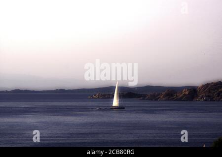 Vela solitaria al tramonto nell'Arcipelago della Maddalena, Sardegna, Italia Foto Stock