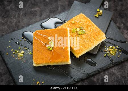 Dessert turco tradizionale come noto Kunefe o Kunafah o Kunafeh o Kunafa Kadayif. Questo è dessert medio orientale fatto pistacchio e crema su Nero Foto Stock