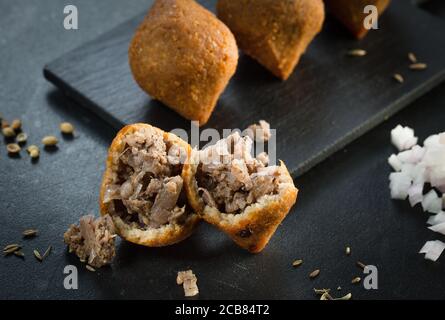 Tradizionale kibbeh arabo-turco-siiriano con agnello e pinoli. Vista dall'alto. Sfondo in legno naturale Foto Stock