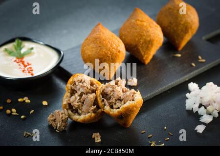 Tradizionale kibbeh arabo-turco-siiriano con agnello e pinoli. Vista dall'alto. Sfondo in legno naturale Foto Stock
