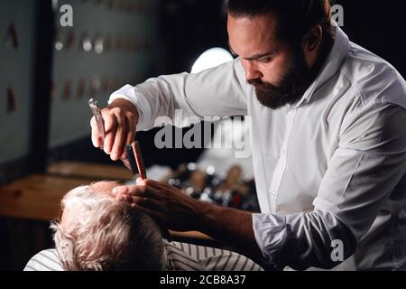 giovane uomo che gestisce un barbiere di successo, primo piano ritagliato vista laterale foto Foto Stock