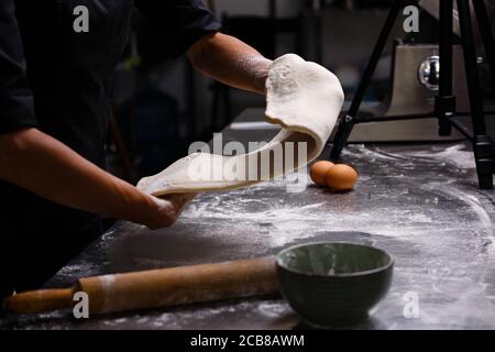 Lo chef prepara dolci in una cucina professionale. Sfondo scuro. Foto Stock