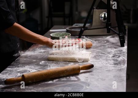 Lo chef prepara dolci in una cucina professionale. Sfondo scuro. Foto Stock