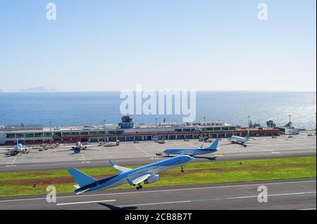 Aeroplani che decolgono alla pista dell'Aeroporto Internazionale di Madeira, tempo luminoso del sole, vista dell'oceano sullo sfondo, Funchal, Portogallo Foto Stock
