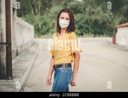 Giovane donna che indossa una maschera medica all'aperto Foto Stock