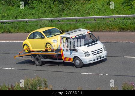 Maggiolino VW Volkswagen giallo su autocarro servizio di recupero guasti commerciali 24 ore su 24; autocarri da trasporto, camion, trasporto, camion, Vettore di carico, veicolo Ford 90 T30, trasporto commerciale europeo, industria, M6 a Manchester, Regno Unito Foto Stock