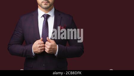 Uomo vestito con giacca e cravatta isolato su sfondo rosso scuro. Immagine per la pubblicità di un negozio di abbigliamento maschile. Un simbolo di successo e di mascolini Foto Stock