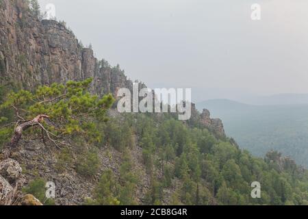 Rocce di Aigir nel fumo di un incendio forestale. Bashkortostan. Foto Stock