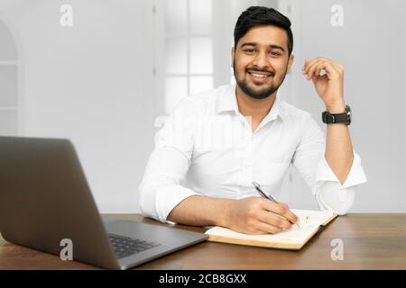 Studente asiatico che studia, impara la lingua, concetto di educazione online. Ritratto di bell'uomo d'affari indiano che usa un computer portatile, che lavora in ufficio Foto Stock