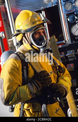 Vigile del fuoco in piena marcia in esecuzione con il tubo flessibile, STATI UNITI D'AMERICA Foto Stock