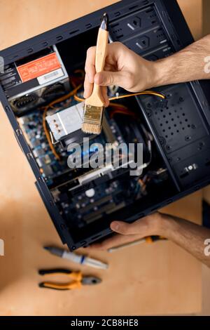 uomo che pulisce il sistema del calcolatore con una spazzola, primo piano la foto ritagliata, servizio del calcolatore Foto Stock