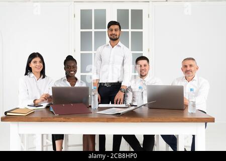 Gruppo di designer sorridenti mentre si lavora intorno a un tavolo da ufficio Foto Stock