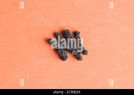 Closeup ad alto angolo di lunghi peppercorn su un arancione sfondo Foto Stock