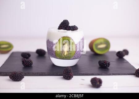 Primo piano di budino di chia con more e kiwi su un bordo sotto le luci Foto Stock