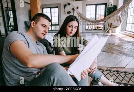 Una giovane coppia gestisce le finanze guardando attraverso la loro banca account Foto Stock
