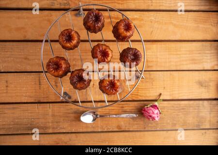 Foto ad alto angolo di pasticceria francese Caneles de Bordeaux on un tavolo di legno Foto Stock