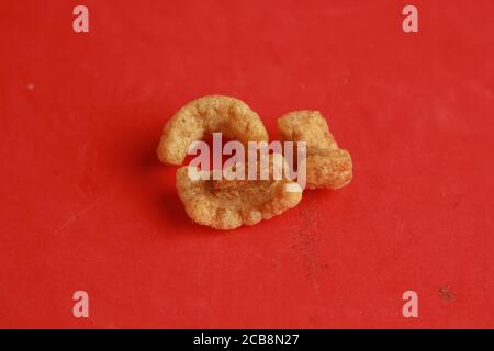 Primo piano di Torreznos tradizionali spagnoli a base di maiale fritto pelle su una superficie rossa Foto Stock