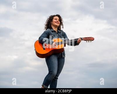 Giovane caucasica che suona felicemente la chitarra Foto Stock