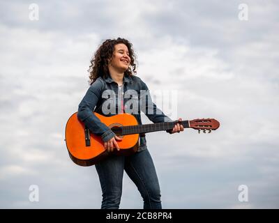 Giovane caucasica che suona felicemente la chitarra Foto Stock