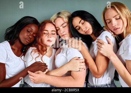 Ritratto di cinque belle donne in jeans in piedi insieme isolati su sfondo grigio Foto Stock