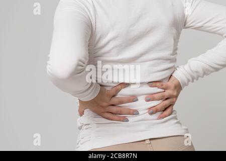 Vista closeup della donna che ha dolore, muscolo o dolore cronico del nervo nella sua schiena dopo il lavoro, isolato. Malattie della colonna vertebrale, scoliosi, osteoporosi Foto Stock