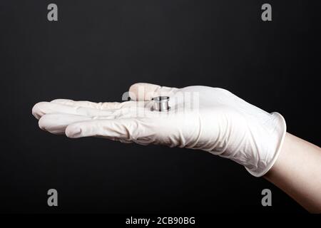 gioielli auricolari, tunnel auricolari color argento in mano su uno sfondo scuro. Foto Stock