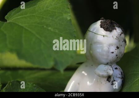 Una bella figurina cupida in porcellana che soffia baciata nel giardino del cortile. Foto Stock