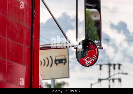 Immagine del logo aziendale della Coca cola. Riflessa nello specchio retrovisore di un camion di consegna. Scena urbana Foto Stock