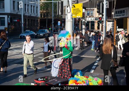 26.09.2019, Sydney, nuovo Galles del Sud, Australia - la gente attraversa un passaggio pedonale nel sobborgo di Haymarket a Chinatown vicino ad un artista di strada. Foto Stock