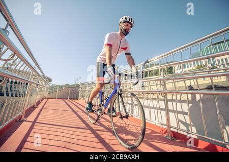 Ciclista in outfit sportivi a cavallo sul ponte Foto Stock