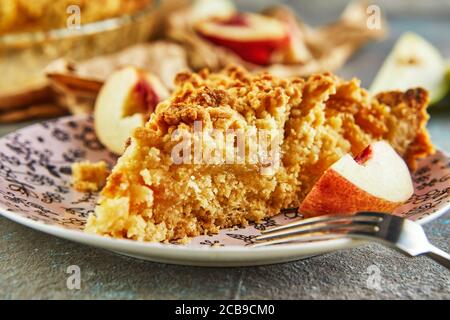 Torte fatte in casa, un pezzo di torta su un piatto con pesche e pere su cemento grigio-blu. Primo piano Foto Stock