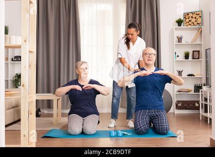 Coppia anziana che fa la terapia fisica con il medico a casa. Assistenza domiciliare, fisioterapia, stile di vita sano per anziani, allenamento e stile di vita sano Foto Stock