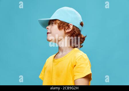 Un bambino in un cappuccio blu guarda verso i capelli rossi Foto Stock