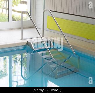 Scale metalliche in una piscina interna Foto Stock